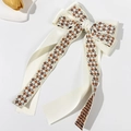 Close-up of cream satin bow hair clip featuring intricate floral embroidery on long ribbons - Beige