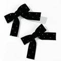 Dettaglio di due fermagli per capelli a fiocco in velluto nero con strass su sfondo bianco - Nero