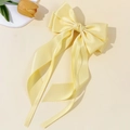 Detail of light yellow satin bow hair clip with long ribbons and elegant silk texture - Yellow