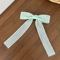 Close-up of mint green tulle bow hair clip with wavy scalloped edges on wood - Light Green