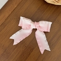 Primer plano de pinza para el pelo con lazo de cinta rosa y blanca sobre fondo de madera - Estilo con Volantes Degradado Rosa y Blanco