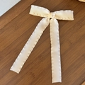 Close-up of cream-white ribbon hair clip with delicate ruffled edges on dark wood surface - Off-white Long Streamer Style