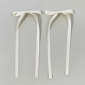 Close-up of creamy white satin bow hair clips with long ribbons and metal hairpins - Beige