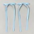 Dettaglio di una coppia di fermagli per capelli con fiocchi di raso azzurro e nastri - Blu