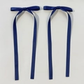 Dettaglio di un paio di fiocchi di raso blu scuro con lunghi nastri eleganti su sfondo grigio - Blu navy