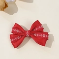 Dettaglio di un fermaglio per capelli con fiocco di raso rosso e ricamo di fiori e cuori - Rosso