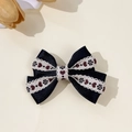 Dettaglio del fermaglio a fiocco blu navy con ricamo floreale e pizzo bianco su beige - Nero