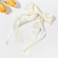 Detalle macro del elegante lazo para el pelo de satén blanco con cintas fluidas - Beige