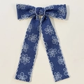 Detalle del lazo de mezclilla azul con bordado de margaritas blancas y borde festoneado - Azul marino
