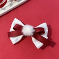 Detail van een feestelijke haarclip met witte bontbal en strik op rode achtergrond - Bordeauxrood