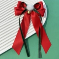 Detalle del lazo rojo de Navidad con pompón blanco y campana dorada sobre un plato - Estilo Festivo con Cinta Larga (3#)