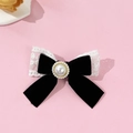 Detailed macro view of a vintage velvet bow hair clip with lace and a central faux pearl - Black