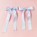 Detail of light blue satin hair clips with long ribbon streamers on pink background - Blue