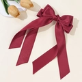 Close-up of wine red grosgrain bow hair clip with scalloped edges and long ribbons - Burgundy