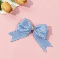 Détail d'un nœud papillon en satin bleu clair avec bords froncés et cœur en cristal - Bleu
