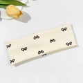Dettaglio della fascia elastica color crema con stampa fiocco nero e tessuto - Beige