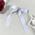 Close-up of light blue satin bow hair clip featuring heart rhinestone and cross pendant - Blue