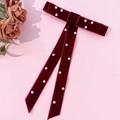 Close-up of deep red velvet bow hair clip with white pearl beads on pink background - Burgundy