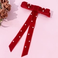 Close-up of red velvet bow hair clip with white pearls and long ribbon on pink backdrop - Red