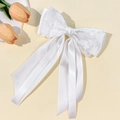 Detailed close-up of white satin and lace bow hair clip with floral embroidery - White