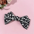 Detailweergave van een retro satijnen strik haarclip met stippen en strepen op roze - Zwart
