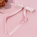 Pink ribbon bow hair clip with lace and white pearl on a solid pastel background - Pink