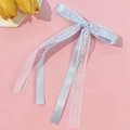 Detailed view of light blue lace bow hair clip with long ribbons on pink background - Blue