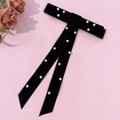 Dettaglio del fiocco per capelli in velluto nero con perle bianche e nastri su sfondo rosa - Nero