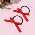 Gros plan sur deux chouchous nœuds en satin rouge avec élastiques noirs sur fond rose - Rouge