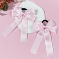 Set mit rosa Satin-Schleifen-Haargummis mit langen Bändern auf einem weißen Tablett - Rosa