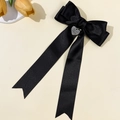 Detailaufnahme einer schwarzen Satin-Haarschleife mit graviertem Herz-Metallanhänger - Schwarz (Silbernes Herz)