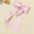 Nahaufnahme einer rosa Satin-Haarschleife mit Herzanhänger und langen fließenden Bändern - Rosa