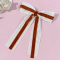 Detailed close-up of brown velvet and white lace bow hair clip with long flowing ribbons - Caramel color