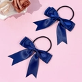 Détail de deux chouchous nœuds en satin bleu marine avec de longs rubans sur fond rose - Bleu marine