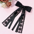 Detail der eleganten schwarzen Spitzen-Haarschleife mit langen Bändern auf rosa Hintergrund - Schwarz