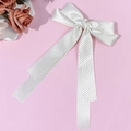 Close-up of elegant white satin bow hair clip with black polka dots and long ribbons - Beige
