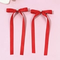 Détail de barrettes nœuds rouges avec perles et longs rubans sur fond rose tendre - Rouge