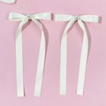 Detalle de lazos de seda crema estilo ballet con perla central sobre fondo rosado - Beige