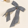 Detail of a black and white checkered bow hair clip with a red rhinestone cherry charm - Black