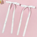 Gros plan de barrettes à nœuds en satin blanc avec longs rubans sur fond rose - Blanc
