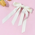 Detail der cremeweißen Satinschleife mit langen Bändern auf hellem rosa Hintergrund - Beige