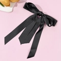 Detailansicht der eleganten schwarzen Satin-Schleife mit langen Bändern auf rosa Hintergrund - Schwarz