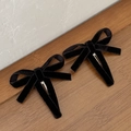 Detail of two black velvet bow hair clips with metal duckbill clips on wooden surface - Black