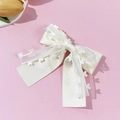 Detalle de un lazo blanco de doble capa con tul de corazones y cinta de raso suave - Beige