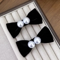 Detalle de pinzas de lazo de terciopelo con perlas en una bandeja de joyas beige - Negro