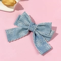 Dettaglio della molletta a fiocco in denim blu con margherite bianche e bordo a contrasto - Azzurro