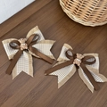 Détail de barrettes nœuds ourson avec motif pied-de-poule et rubans bruns sur bois - Style Ours