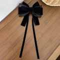 Details einer eleganten schwarzen Samtschleife mit langen Bändern auf Holzoberfläche - Schwarz