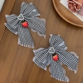 Détail de barrettes noeud en dentelle fraise avec boucle coeur sur bois rustique - Noir