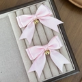 Detail van roze satijnen haarstrikken met gouden bellen op een fluwelen dienblad - Roze